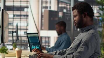 Male executive analyst finalizes a financial report and reviews data, developing a forecast for organizational progress. Black man engaged in task management and strategy planning. Camera A. video