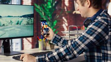 Man at home having fun looking at social media reels done by online content creators. Employee taking break from work to use mobile social network app, screensaver activating on PC, camera B video