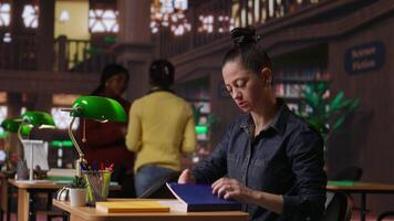 Professional author and librarian working on new notes in a public library, focused on academic resources and guidance for success. Woman collecting educational information. Camera B. video