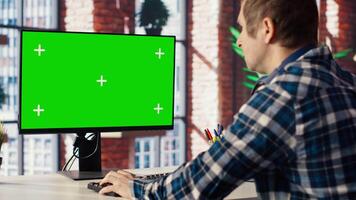 Teleworker in apartment home office using mockup PC to analyze sales report and plan business development. Man working from home doing project research, typing on isolated screen computer, camera B video