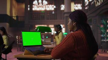 svart bibliotekarie skriver på bärbar dator med krom nyckel i en tyst offentlig bibliotek, tillägnad till organisering studie Resurser och mentor studenter i deras akademisk resa med stolthet. kamera a. video