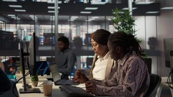 African american businesswomen collaborating on monthly revenue balance calculation, strategizing a plan for enterprise development. Team of executive staff evaluating analytics on pc. Camera B. video