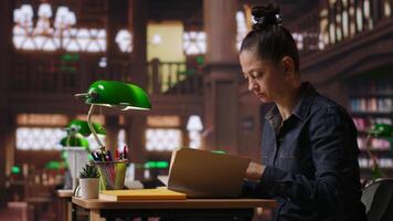 kvinna handledare läsning en bok och håller på med en kort till komplett henne anteckningar, skapande exakt inlärning material för henne privat lektioner och mentor i ett akademisk miljö. kamera b. video