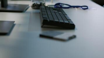 Close up of computer peripherals on server room desk used by employees working to ensure minimal downtime. Hard disk, keyboard and tablet in data center office used for monitoring performance video