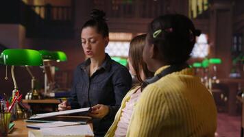 kvinna mentor tillhandahålla instruktion till olika elever under privat lektioner på de bibliotek, bistå med läxa och skola projekt i de studie område. handledning session för vägledning. kamera b. video