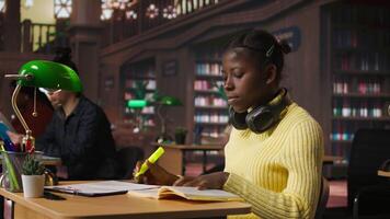 Teenage girl at the library highlighting relevant phrases for study session, marking paragraphs from class notes to learn for the exam. Using a fluorescent pen as a studying technique. Camera A. video