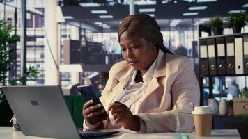 Female CEO discussing business ideas with her team on social media, receiving project updates form employees via text messages. Black goal oriented entrepreneur with determination. Camera B. video