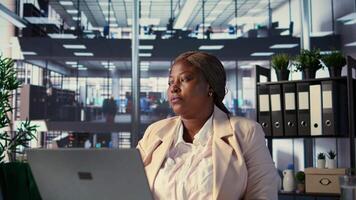 Ambitious CEO leader taking a break and relaxing in her own office, looking out the window at urban corporation center. Entrepreneur resting in her leader chair, success story. Camera B. video