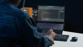 Software developer writes code on laptop screen while in apartment office using Java programming languages. Programmer remotely working on fixing database errors while working from home, camera A video