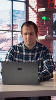 Man seated at home office desk using laptop, answering phone call while checking emails displayed on screen. Worker in telephone call with friend at work while reading messages in inbox, camera A video