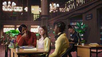Cheerful diverse classmates sharing a high five during private lessons with tutor in the library, finishing team project. Elementary school pupils feeling satisfied with academic progress. Camera A. video