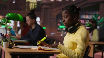 Teenage girl at the library highlighting relevant phrases for study session, marking paragraphs from class notes to learn for the exam. Using a fluorescent pen as a studying technique. Camera B. video