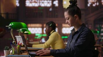 porträtt av en självsäker bibliotekarie arbetssätt på henne bärbar dator i en offentlig bibliotek, tillhandahålla akademisk Resurser och vägledning. specialist utvärdera inlärning material inom de databas. kamera b. video