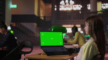 Focused schoolgirl engaged in academic tasks with green screen at a library, working on school assignments with her laptop. Solving class work tasks, searches information on internet. Camera A. video