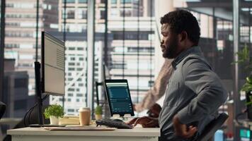 African american company worker taking a break to stretch his back in the office, trying to relieve pain after working with an uncomfortable chair and an incorrect posture. Inflammation. Camera A. video