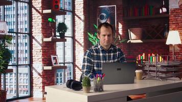Freelancer in home office sitting at desk and typing on laptop keyboard. Remote employee using electronic device to do customers relations job online, answering inquiries, camera A video