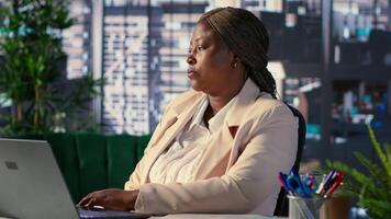 Black business director resting in her high end CEO chair after a project, reminiscing about her career development and achievements. Female leader taking a break to relax at work. Camera A. video