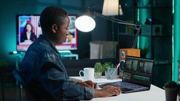 Remotely working videographer doing montage using specialized software applications. African american editor using editing tools on laptop to cut movie project footage in office, camera A video