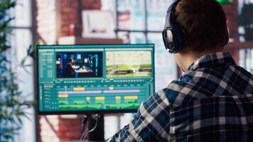 editor wearing headphones doing montage, using specialized software application, zoom in shot. Freelancer using editing tools on PC to cut movie project footage, camera B closeup video