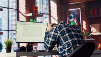 Software developer at computer waiting for code to finish compiling, yawning, feeling bored. Impatient man tired to wait for algorithms building scripts to finish, camera B video