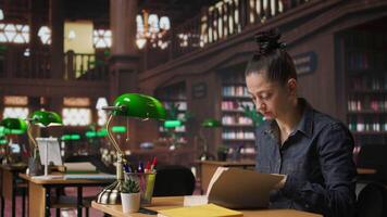 Woman tutor reading a book and doing a brief to complete her notes, creating accurate learning materials for her private lessons and mentoring in an academic environment. Camera A. video