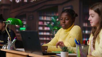Primary school pupils in a library discuss during an online seminar, using tech to connect with educator and classmates for an interactive virtual chat. Remote lesson via web conference. Camera B. video