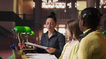 kvinna mentor tillhandahålla instruktion till olika elever under privat lektioner på de bibliotek, bistå med läxa och skola projekt i de studie område. handledning session för vägledning. kamera a. video