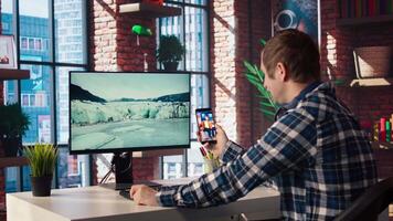 Man at home having fun looking at social media reels done by online content creators. Employee taking break from work to use mobile social network app, screensaver activating on PC, camera A video