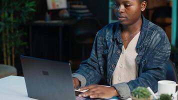 Entrepreneur working from home, using laptop and writing notes on paper. Remote worker in personal apartment office answering emails and transcribing important info on notepad, camera A video