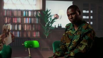 African american soldier in military uniform sits with an expert, viewing a Rorschach test illustration to share feelings and discuss trauma. PTSD and shell shock counseling session. Camera B. video