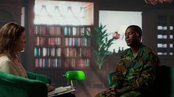 Black military officer in army uniform attends counseling session, looking distressed and opening up about post traumatic combat stress. War soldier dealing with shell shock. Camera B. video