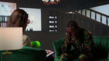 Distraught soldier in tears sharing his struggles with war PTSD, attends therapy session with expert for rehabilitation. Psychological support and society reintegration for veterans. Camera A. video