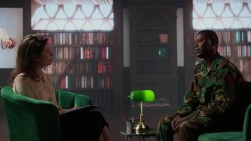 African american soldier looks distressed during a counseling session for trauma recovery, trying to open up and share his grief. PTSD support and mental health treatment for combatant. Camera A. video