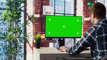 Teleworking man in living room home office using chroma key computer to plan business development. Remote worker doing project research, typing on green screen device keyboard, camera B video