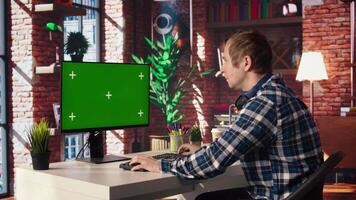 Teleworker in apartment home office using mockup PC to analyze sales report and plan business development. Man working from home doing project research, typing on isolated screen computer, camera A video
