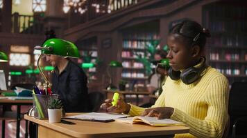 Black preteen pupil underlining key words and phrases for the learning session at the library, creating a summary to retain information easier. Focused scholar studying. Camera A. video