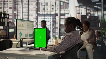 Female manager seated at workstation with green screen on devices, working on solving administrative tasks for enterprise growth. Developing performance metrics to support firm goals. Camera B. video