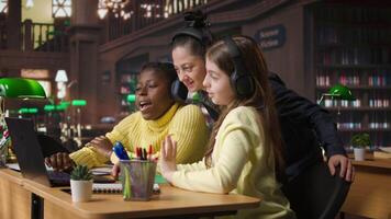 Young students and tutor attending an online class via call in the library, focused on distance learning and completing a school assignment with other classmates on the network. Camera A. video