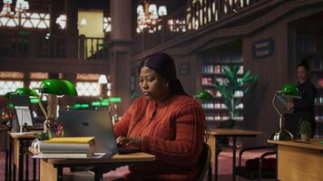 African american tutor preparing documents and learning materials for teaching session in school library. Clever professor providing academic resources for mentoring in the study area. Camera A. video