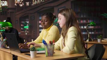 Primary school pupils in a library discuss during an online seminar, using tech to connect with educator and classmates for an interactive virtual chat. Remote lesson via web conference. Camera A. video
