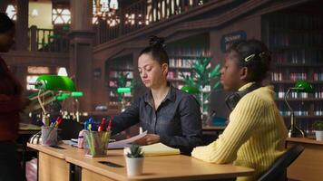 Caucasian tutor guiding elementary school girl at a library desk, providing private lessons to aid in their academic development with work books and notes. Teacher discussing with scholar. Camera A. video