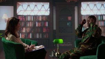 Black combat veteran faces grief and trauma crying at therapy session, addressing PTSD and talking about combat scenes. Sad shocked soldier shares war flashbacks with counselor. Camera A. video