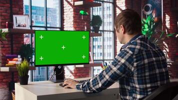 Teleworking man in living room home office using chroma key computer to plan business development. Remote worker doing project research, typing on green screen device keyboard, camera A video