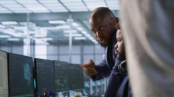 Data center manager helps intern implement AI predictive maintenance systems. Server farm supervisor checks work done by employee using artificial intelligence to identify hardware failures, camera A video
