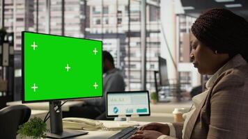 Woman at her desk working on data analysis next to mockup display, engaged in business tasks and budget management to drive effective corporate strategy. Analyst reads reports numbers. Camera B. video