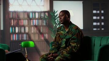 Female psychologist assists a black soldier in a counseling session, focusing on PTSD and trauma after combat distress. Mental health support for army veterans, grief and guilt. Camera B. video