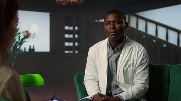 Doctor in white coat opening up about his medical career struggles, suffering from anxiety and mental health issues. Therapist listens with empathy, discussing grief and emotional support. Camera A. video
