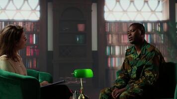 African american soldier looks distressed during a counseling session for trauma recovery, trying to open up and share his grief. PTSD support and mental health treatment for combatant. Camera B. video