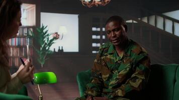 African american soldier in military uniform sits with an expert, viewing a Rorschach test illustration to share feelings and discuss trauma. PTSD and shell shock counseling session. Camera A. video