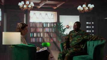 Portrait of war veteran meeting with a therapist to discuss about grief and distress due to PTSD and battle trauma, shell shock and mental disorder. Depressed trooper at counseling. Camera B. video